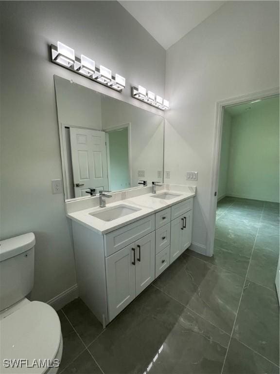 full bath featuring a sink, baseboards, toilet, and double vanity