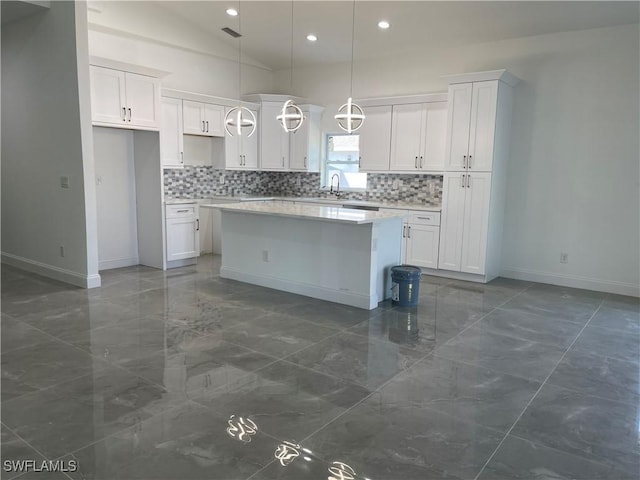 kitchen with marble finish floor, a sink, backsplash, a kitchen island, and white cabinets