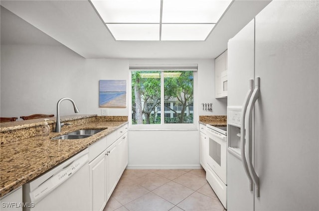 kitchen featuring light stone counters, light tile patterned flooring, white appliances, a sink, and white cabinets