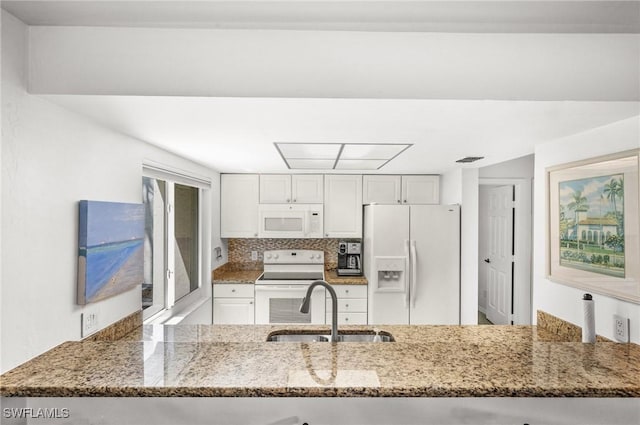 kitchen featuring white appliances, stone countertops, and a sink