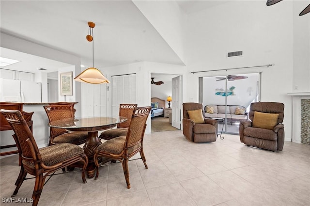 dining room featuring visible vents, ceiling fan, a high ceiling, and light tile patterned floors