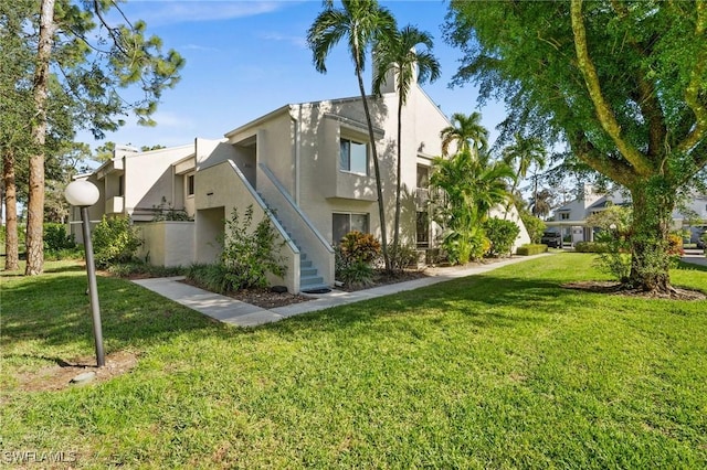 exterior space featuring a yard, stairway, and stucco siding