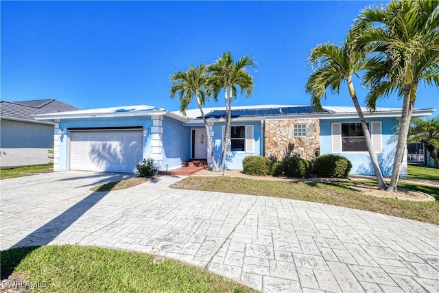 ranch-style home with solar panels, stucco siding, metal roof, decorative driveway, and a garage