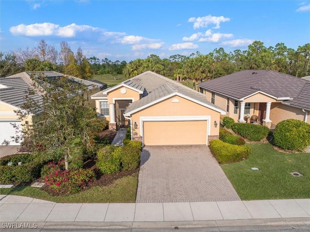 view of front of home featuring a garage, a front yard, decorative driveway, and stucco siding