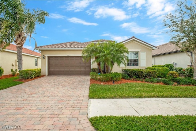 view of front of home with a tiled roof, decorative driveway, a garage, and stucco siding