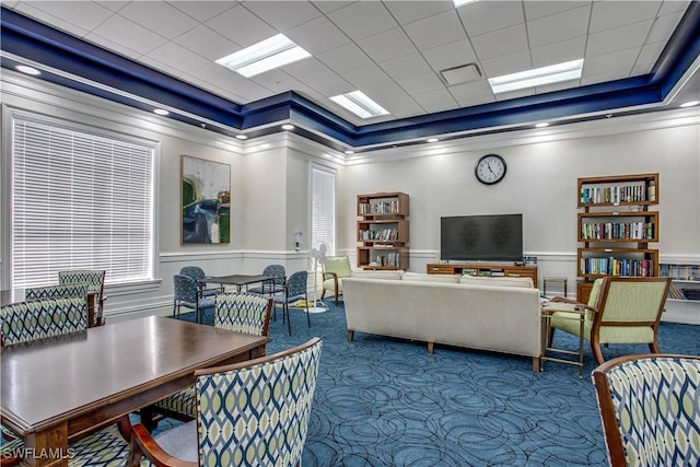 interior space featuring carpet flooring, ornamental molding, a tray ceiling, and a wainscoted wall