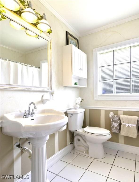 bathroom with toilet, tile patterned flooring, ornamental molding, and baseboards