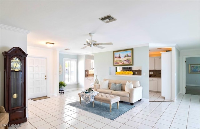 living room featuring light tile patterned floors, baseboards, visible vents, and crown molding