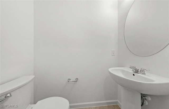 half bath featuring toilet and baseboards