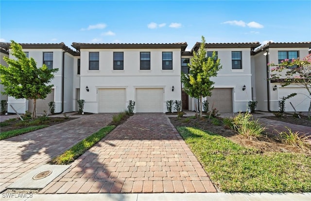 view of front of home featuring a garage, a tiled roof, decorative driveway, and stucco siding