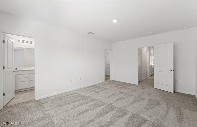 unfurnished bedroom with baseboards, a spacious closet, visible vents, and light colored carpet