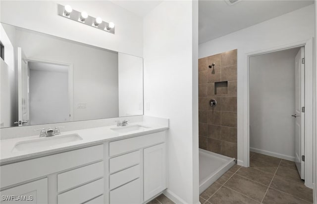 bathroom featuring a tile shower, double vanity, a sink, and tile patterned floors