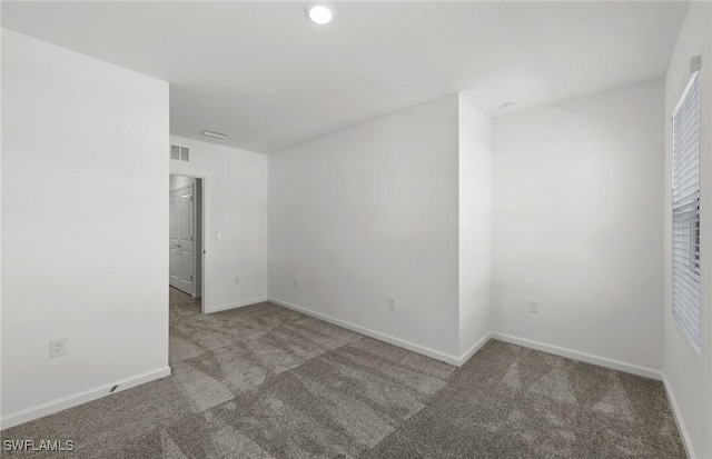 carpeted spare room with visible vents and baseboards