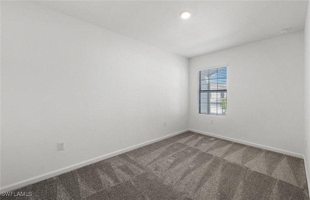 carpeted spare room featuring baseboards