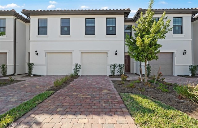 view of front facade with a garage, decorative driveway, and stucco siding