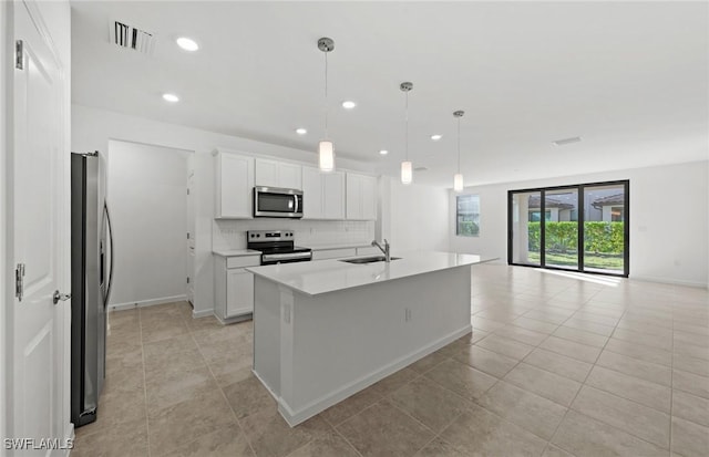 kitchen featuring a sink, white cabinets, open floor plan, appliances with stainless steel finishes, and backsplash