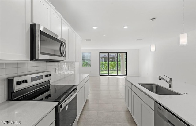 kitchen featuring decorative backsplash, appliances with stainless steel finishes, hanging light fixtures, light countertops, and a sink