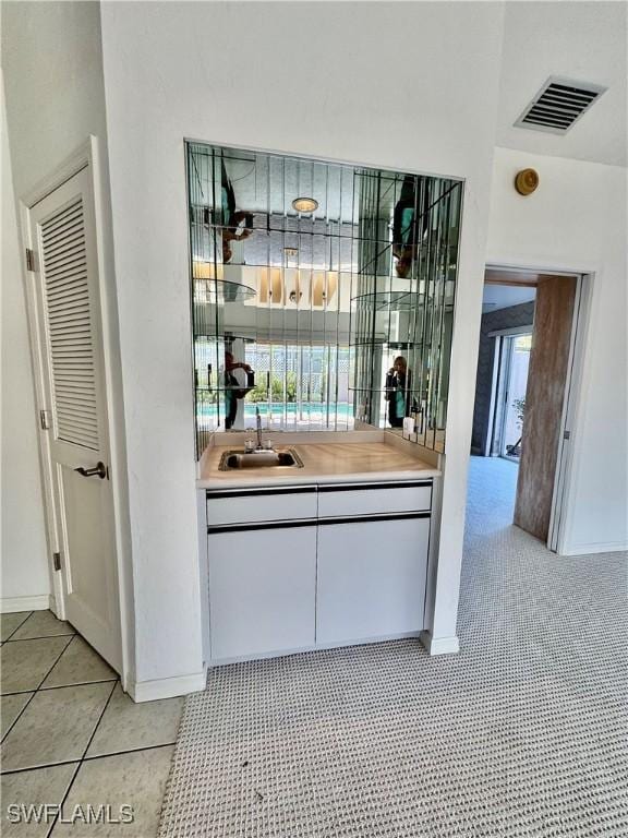 bar featuring light tile patterned flooring, visible vents, and a sink