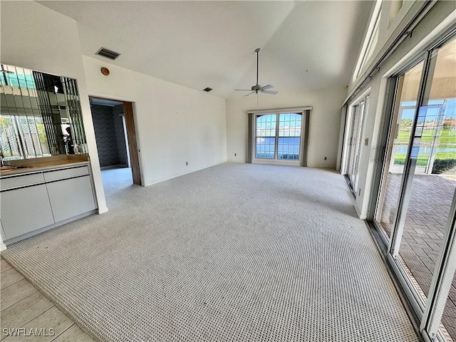 empty room featuring light colored carpet, high vaulted ceiling, visible vents, and ceiling fan