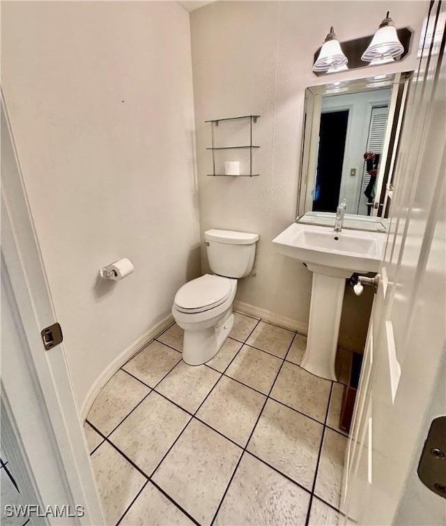 bathroom featuring baseboards, toilet, and tile patterned flooring