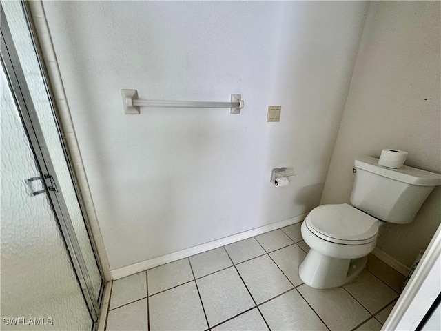 full bath featuring tile patterned flooring, a shower stall, toilet, and baseboards