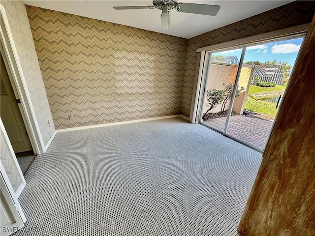 carpeted spare room featuring wallpapered walls, baseboards, and ceiling fan