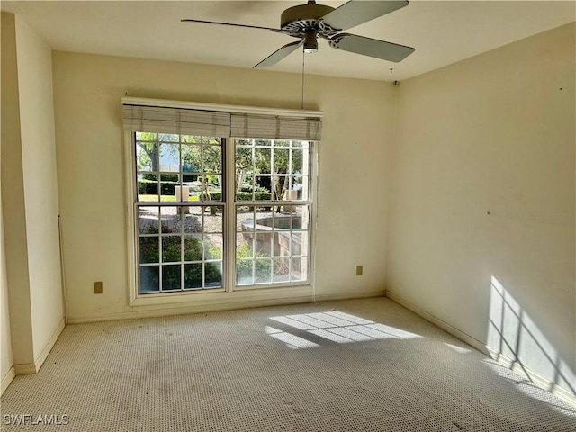 carpeted spare room with plenty of natural light, baseboards, and a ceiling fan