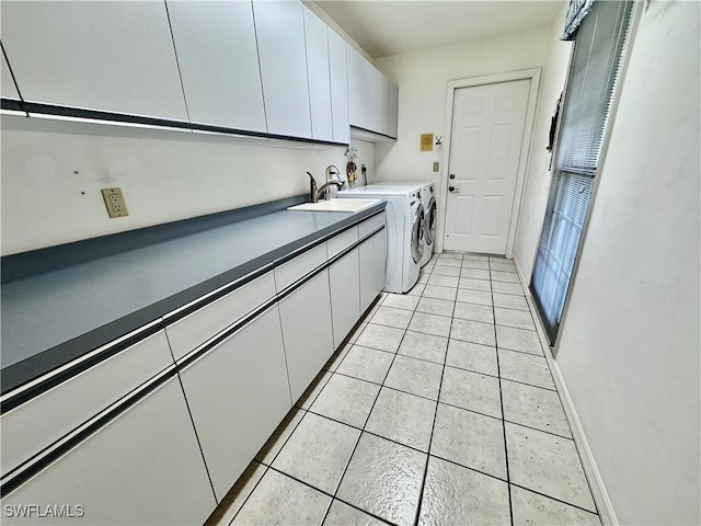 laundry area featuring light tile patterned floors, baseboards, cabinet space, a sink, and washer and dryer