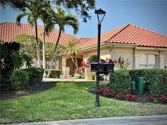 mediterranean / spanish-style house with a garage, stucco siding, a front yard, and a tile roof