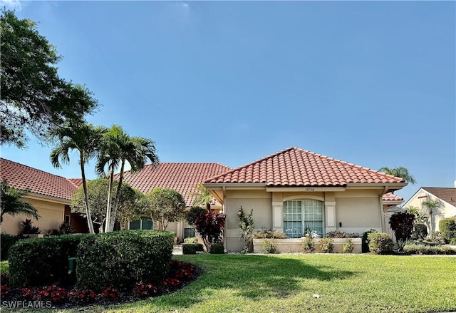 mediterranean / spanish home featuring stucco siding, a tile roof, and a front yard