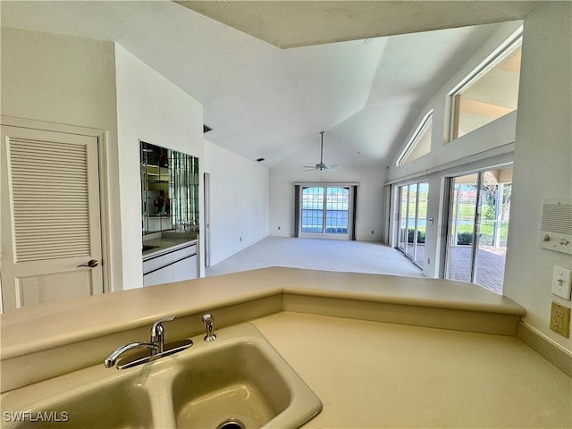 kitchen with ceiling fan, open floor plan, vaulted ceiling, carpet floors, and a sink