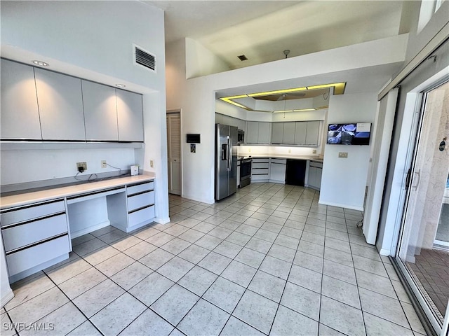 kitchen featuring visible vents, gray cabinets, built in desk, stainless steel appliances, and light countertops