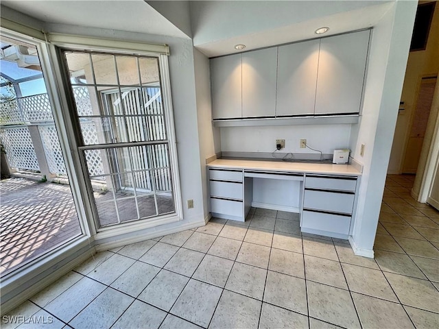 interior space with light tile patterned floors, built in desk, and baseboards