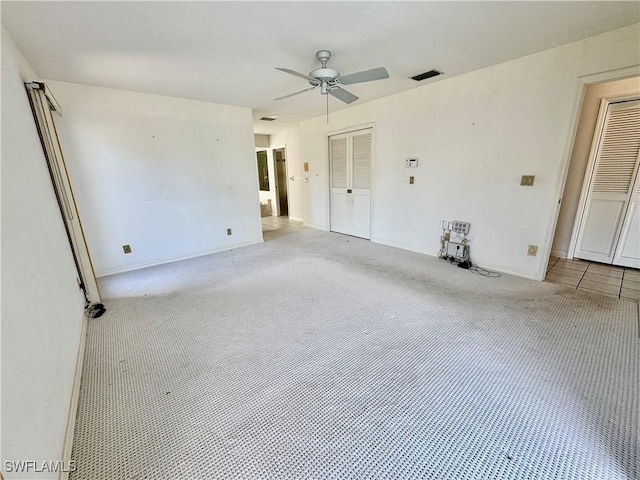 unfurnished room with visible vents, carpet floors, and ceiling fan