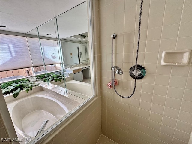 bathroom with tiled shower and a sink