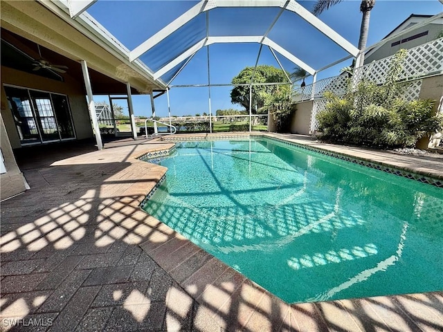 pool with glass enclosure, a patio, and a ceiling fan