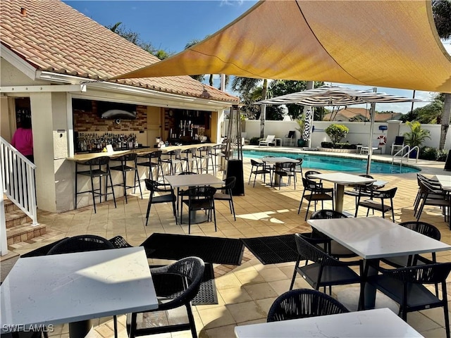 view of patio / terrace featuring outdoor dining area, fence, a fenced in pool, and outdoor dry bar