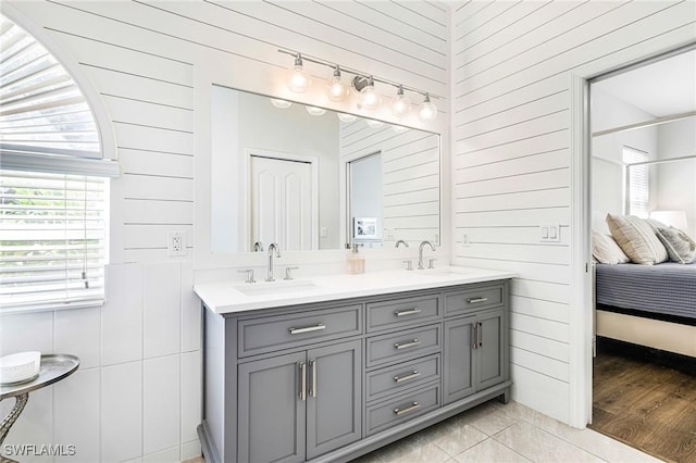 ensuite bathroom featuring ensuite bathroom, double vanity, wood finished floors, and a sink