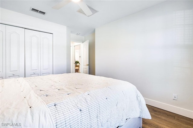 bedroom with dark wood-style floors, baseboards, visible vents, and a closet