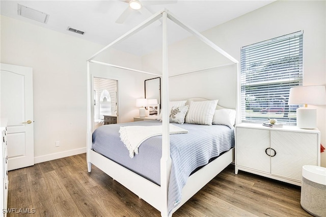 bedroom with baseboards, visible vents, and wood finished floors