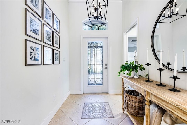 foyer with a chandelier, baseboards, and light tile patterned floors