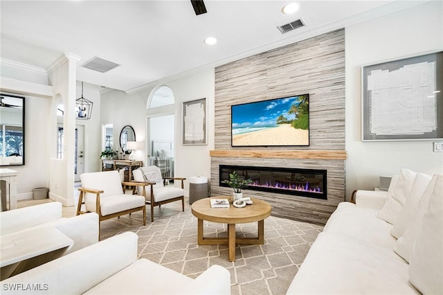 living area featuring a large fireplace, visible vents, baseboards, ornamental molding, and recessed lighting