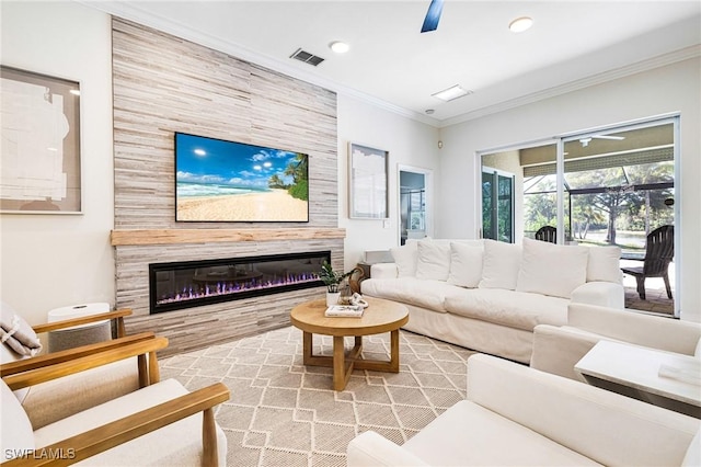 living area featuring visible vents, a ceiling fan, a glass covered fireplace, a sunroom, and crown molding