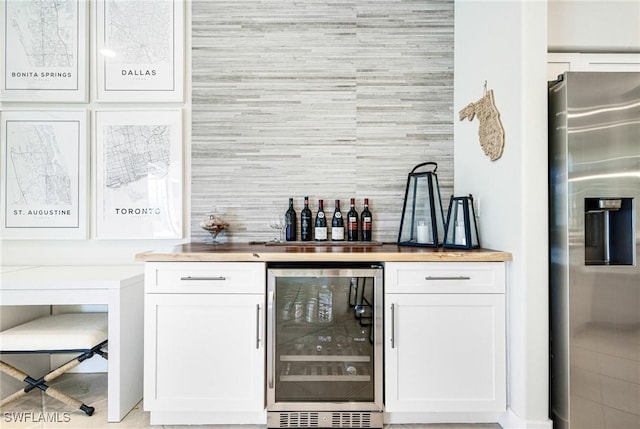 bar with wine cooler, stainless steel fridge, and a bar