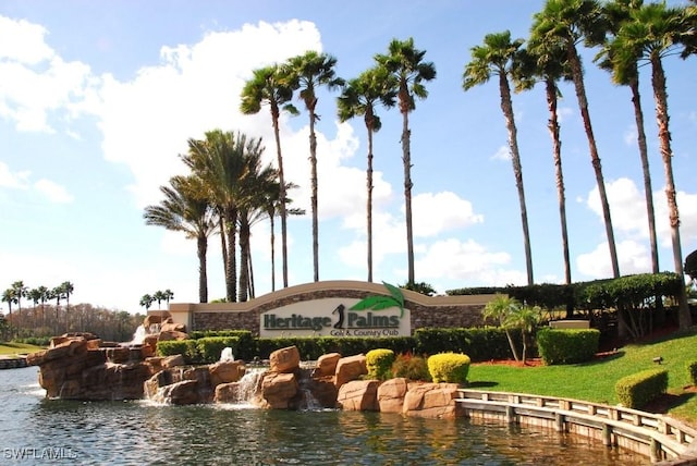 community sign featuring a lawn and a water view