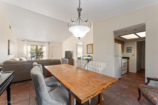 dining room featuring visible vents, dark tile patterned floors, and vaulted ceiling