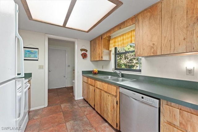 kitchen featuring baseboards, freestanding refrigerator, a sink, dishwasher, and dark countertops