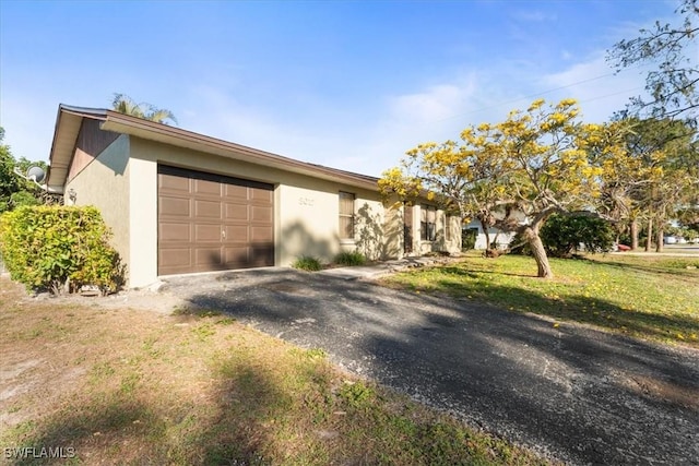 view of front facade featuring stucco siding, a front lawn, an attached garage, and driveway