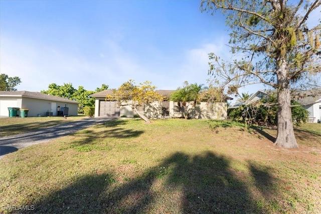 view of yard featuring an attached garage and driveway