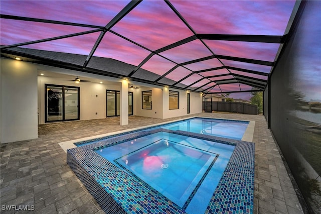 view of pool featuring a patio, glass enclosure, an in ground hot tub, fence, and a ceiling fan